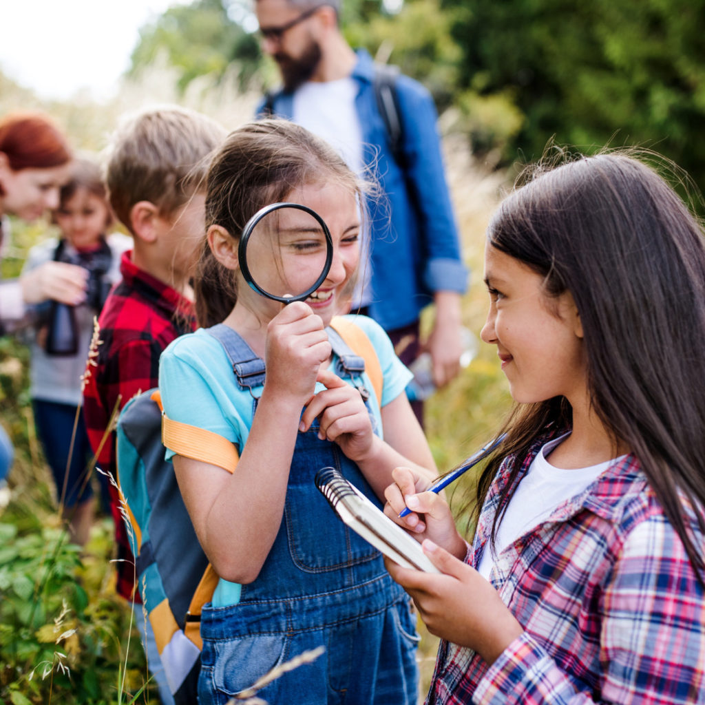 hybrid students outdoors magnifying glass